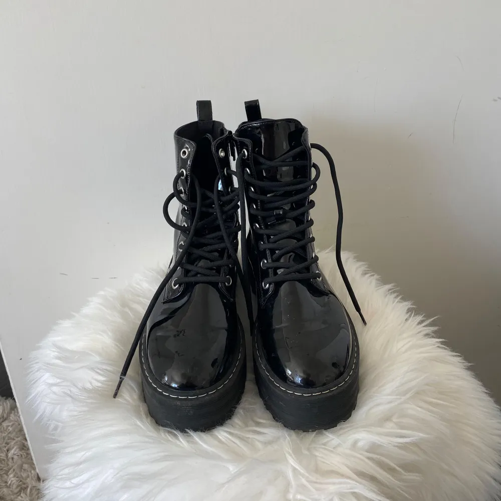 Säljer ett par snygga svarta boots i lackat material. De har en rejäl platåsula och snörning framtill för en cool look. Perfekta för höst och vinter, och de ger en edgy touch till vilken outfit som helst.. Skor.