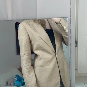 Beige kavaj - Säljer en snygg beige kavaj i normal passform. Den har långa ärmar och stängs med knappar framtill. Perfekt för både vardag och fest!