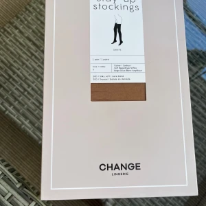 Stay-up strumpor från Change Lingerie - Säljer ett par stay-up strumpor i beige från Change Lingerie. De har en vit spetskant upptill. oanvända i originalförpackning. Pris i butik 159kr.