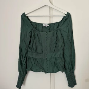 Grön blus - Säljer min jättefina blus från NAKD då den inte passar. Har enbart testat den men inte kunnat använda den då den är för liten. Hoppas den får mer användning hos någon annan 🥰 frakten står köparen för🫶🏻