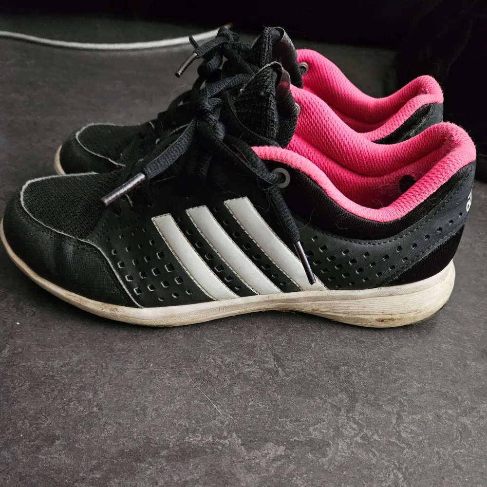 Använda Adidas sportskor i svart och rosa ,deffekter på utsidan men dom har mycket mer att ge .Slitage på insidan men inget som störs utseendemässigt. Skor.