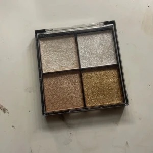 Highlighter-palett med fyra nyanser - Säljer en superfin highlighter-palett med fyra olika skimrande nyanser. Perfekt för att ge ansiktet en strålande glow! Paletten innehåller en ljus silver, en vit, en guldig och en bronzig nyans. Kompakt och lätt att ta med sig i väskan. Perfekt för både vardag och fest!