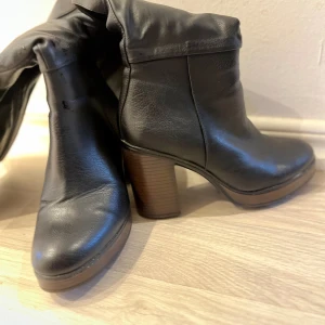 Svarta skinnstövlar med klack - Säljer ett par snygga svarta stövlar i skinn med hög klack. (Skinnimitation / konstläder)  De har en dragkedja på sidan för enkel på- och avtagning. Perfekta för höst och vinter, och de ger en elegant touch till vilken outfit som helst.