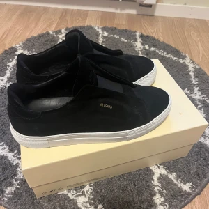 Svarta sneakers från Axel Arigato - Säljer ett par stilrena svarta sneakers från Axel Arigato. Skorna är i mocka med en vit sula som ger en snygg stil dessutom är dem använda bara 3-4  gånger anledningen till att jag säljer dem är för att dem är för små för mig pris kan diskuteras.