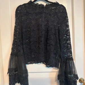 Svart spetsblus med vida ärmar - Super fin spets topp med volang ärm i storlek M.