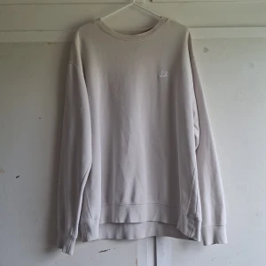 Beige sweatshirt från Nike - Säljer en snygg och bekväm beige sweatshirt från Nike. Den är i storlek XL och har en broderad Nike-logga på bröstet. Perfekt för höst och vinter, och den är i nyskick. Tröjan är långärmad och gjord av mjukt bomullsmaterial. 