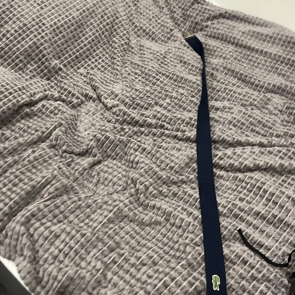 Säljer ett snyggt blått bälte från Lacoste med en stilren silverfärgad spänne. Bältet har den klassiska Lacoste-krokodilen broderad i grönt och vitt. Perfekt för att ge en sportig touch till din outfit!. Övrigt.