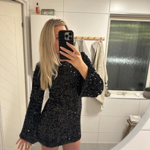 Svart glittrig klänning från Loavies - Snygg svart klänning från Loavies med glittriga paljetter och långa ärmar. Klänningen har dragkedja i ryggen. Endast använd 1 gång. Nypris 1000 kr