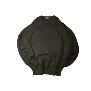 Svart tröja från GANT - Säljer en stilren svart tröja från GANT med v-ringning och broderad logga på bröstet. Perfekt för en avslappnad men ändå snygg look. Tröjan har långa ärmar och ribbade muddar.