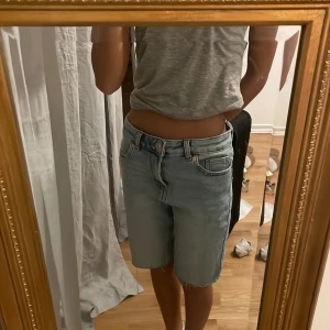 Ljusblå jeansshorts från Amisu - Säljer ett par ljusblå jeansshorts från Amisu. De har en klassisk femficksdesign och är knälånga med en knapp och dragkedja framtill. Perfekta för en avslappnad stil.