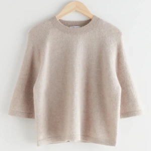 Beige stickad tröja - Mysig beige stickad tröja med trekvartsärm och rund hals. Perfekt för kyliga dagar och enkel att matcha med olika outfits.