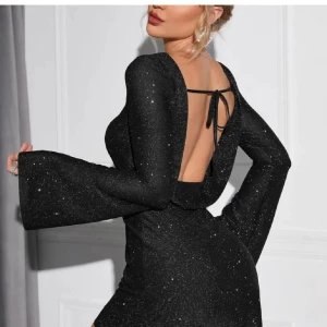 Svart glittrig klänning med öppen rygg - Snygg svart glittrig klänning med öppen rygg och långa ärmar. Passar bra nu till nyår😍. Klänningen har en elegant passform och knytning i ryggen.🤍⭐️ använd endast en gång