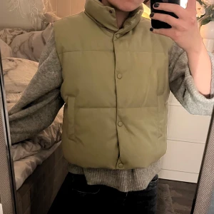 Dunväst med knappar - Säljer en stilren ljus beige-grön dunväst med knappar!! Västen har en hög krage och två fickor framtill. Perfekt för kyligare dagar. Jackan är som ny!! Skriv till mig privat för frågor eller mer bilder 🫶🏻🫶🏻  