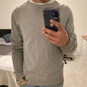 Grå tröja från Paul & Friends - Säljer en stilren grå tröja från Paul & Friends i storlek S. Tröjan har en rund halsringning och ribbade muddar vid ärmslut och nederkant. Perfekt för en avslappnad look.