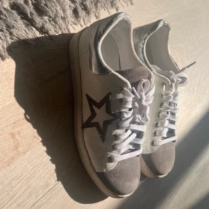 Grå och vita sneakers med stjärndetalj - Snygga sneakers i grått och vitt med stjärndetalj på sidan. Skorna har snörning och en bekväm passform, perfekta för en avslappnad stil⭐️