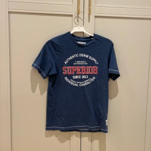 Blå t-shirt med tryck från Produkt - Snygg blå t-shirt från Produkt med ett tryck i vitt och rött på framsidan. 