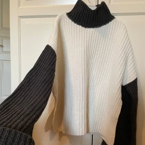 Vit och grå stickad polotröja - Säljer en mysig stickad polotröja i vitt och grått. Tröjan har en hög krage och långa ärmar i kontrasterande färger. Perfekt för kyliga dagar!