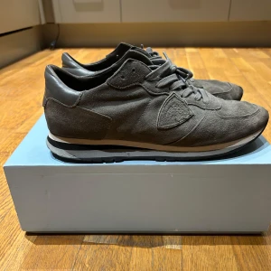 Grå sneakers från Philippe Model - Snygga grå sneakers från Philippe Model i mocka med snörning. Skorna har en stilren design med en bekväm sula och diskreta detaljer. Perfekta för en avslappnad stil. Inte det bästa skicket men ändå snygga. Priset kan såklart diskuteras. Fråga gärna för mer bilder. Allt ORG får man. 