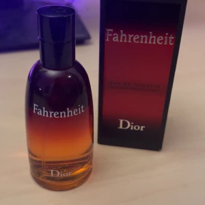 Fahrenheit Eau de Toilette från Dior - Säljer en flaska Fahrenheit Eau de Toilette från Dior. Flaskan har en elegant design med en gradient från rött till orange och svart kork. Doften är känd för sina varma och kryddiga toner.
