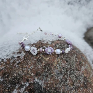 ~Handgjort lila och vitt armband~ - Ett lila och vitt armband med blommor. Perfekt för att liva upp sin outfit, framförallt om du gillar lila. Armbandet har smyckeslås och kedja i silver.