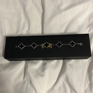 Armband med fyrklöverdesign från Kejsar - Sprillans nytt armband från Kejsar med svart fyrklöverdesign och silverfärgad kedja. Perfekt för att ge en stilren touch till din outfit. Kommer i en snygg svart förpackning med Kejsar-logga. Nypris 1200. Storlek 19cm