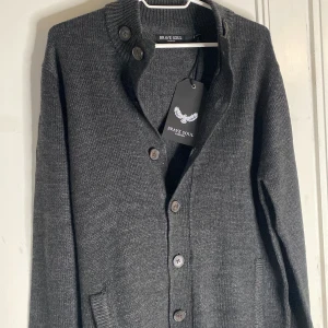 Cardigan(ny med tags) - Go cardigan ifrån Brave soul. Den är ny med tags. Modellen är 187 väger 81 ca(den är lite liten på honom). Mörkgrå färg men har även en till i annan färg i min profil. Priset kan diskuteras och tveka inte på att höra av er vid minsta lilla fundering! Mvh Armadio