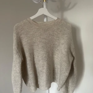 Beige stickad tröja - Mysig beige stickad tröja med rund hals och långa ärmar. Lite nopprig men annars väldigt skön. Köpt från chiquelle. Står ingen storlek på tröjan men skulle säga storlek 36-38