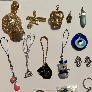 Nyckelringar och hängen - Samling av olika nyckelringar och hängen, inklusive en glittrig guldfärgad keps, en guldfärgad pistol, en krona, ett blått öga, fatimas hand, blåa ankaren, finns en gul också. Perfekt för att dekorera väskor, nycklar eller halsband.                   5-20kr styck om du vill köpa allt så ger jag dig ett pris. 