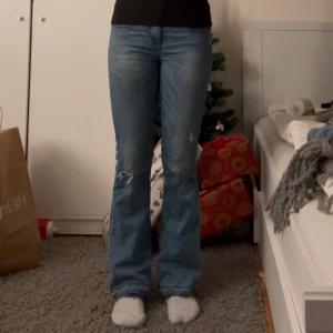 Blå bootcut jeans - Snygga blå bootcut jeans med lite slitningar på knäna, har sprättat upp de längst ner för att du ska passa i längden och jag är 164. Texten med storleken har försvunnit men jag brukar ha W26 L30 och de passar perfekt, low waist