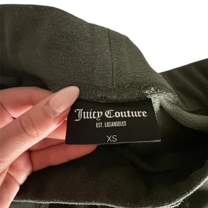 Gröna mjukisbyxor från Juicy Couture - Snygga gröna mjukisbyxor från Juicy Couture med elastisk midja och praktiska bakfickor med knappar. Perfekta för en avslappnad stil. Nypris 1200kr, säljer för 499kr🤍