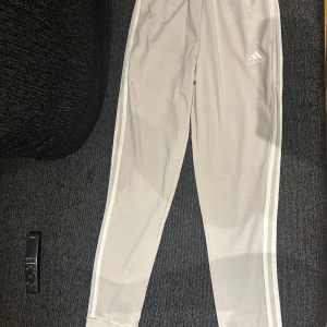 Vita träningsbyxor från Adidas - Snygga träningsbyxor från Adidas med en regular fit och avsmalnande ben. Byxorna har elastisk midja och är fullängd. Perfekta för träning eller en avslappnad dag. Med prislapp 