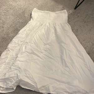 Vit kjol från Gina Tricot - Säljer en vit kjol från Gina Tricot med elastisk midja. Kjolen är luftig och perfekt för varma dagar. Den har en enkel och stilren design som passar till många olika tillfällen.