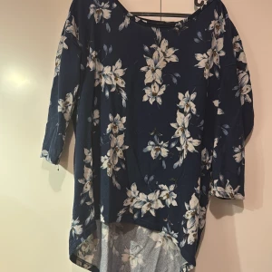 Blommig blus i blått och vitt - Säljer en vacker blommig blus i blått med vita blommor. Blusen har trekvartsärmar och en lös passform, perfekt för vår och sommar. Den är tillverkad i ett mjukt och bekvämt material.