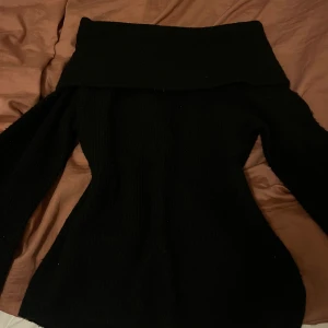 Svart offshoulder tröja från H&M - Snygg svart offshoulder tröja från H&M. Perfekt för en stilren look med sin eleganta design. Tröjan har långa ärmar och en bred krage som ger en unik touch. Passar utmärkt till både jeans och kjol.