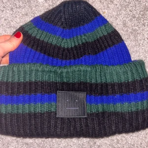 Acne studios mössa - Snygg randig mössa i svart, blått och grönt från Acne studios. Perfekt för att hålla värmen med stil💗✨ Är precis som ny och köpte den för ca 1 700 kr. 