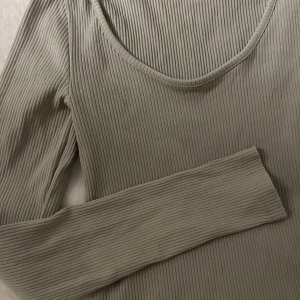Ljus grön ribbad topp  - Ljus grön ribbad topp med långärmad design. Rundad halsringning med stretchigt material.