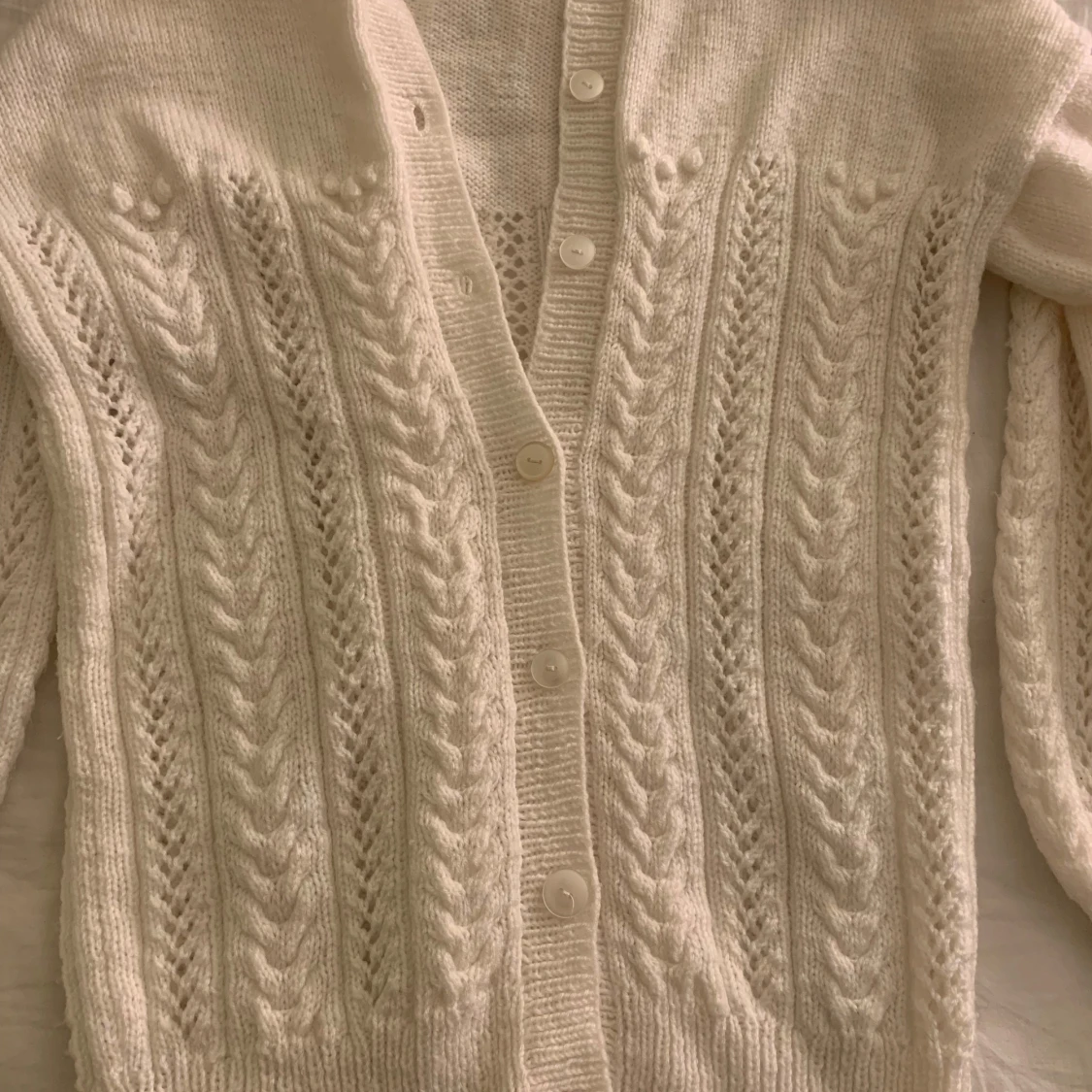 Vit stickad kofta med flätmönster