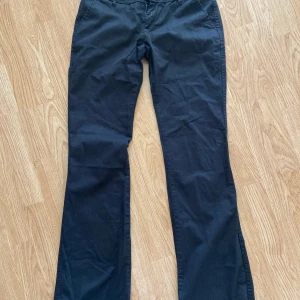 Lågmidjade kostymbyxor/chinos - Svarta lågmidjade kostymbyxor/chinos, ganska tunt material. Lite stretchiga. Storlek 38 och är normala i storleken. Skrolla ner för mått:)  Midja: 40 cm Innerbenslängd: 85 cm Ytterbenslängd: 104 cm