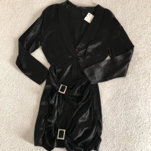 ZARA svart festklänning med diamantstenar - Otroligt snygg klänning från ZARA med två stora diamant-fyrkanter. Ny med prislapp. Kan eventuellt finnas någon tråddragning då klänningen är i satin.