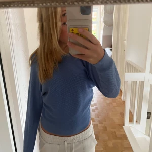 Blå stickad tröja från Mango - Säljer en superfin blå stickad tröja från Mango i storlek XS. Den har en unik design med knytning i ryggen och långa ärmar. Perfekt för både vår och höst! 💙