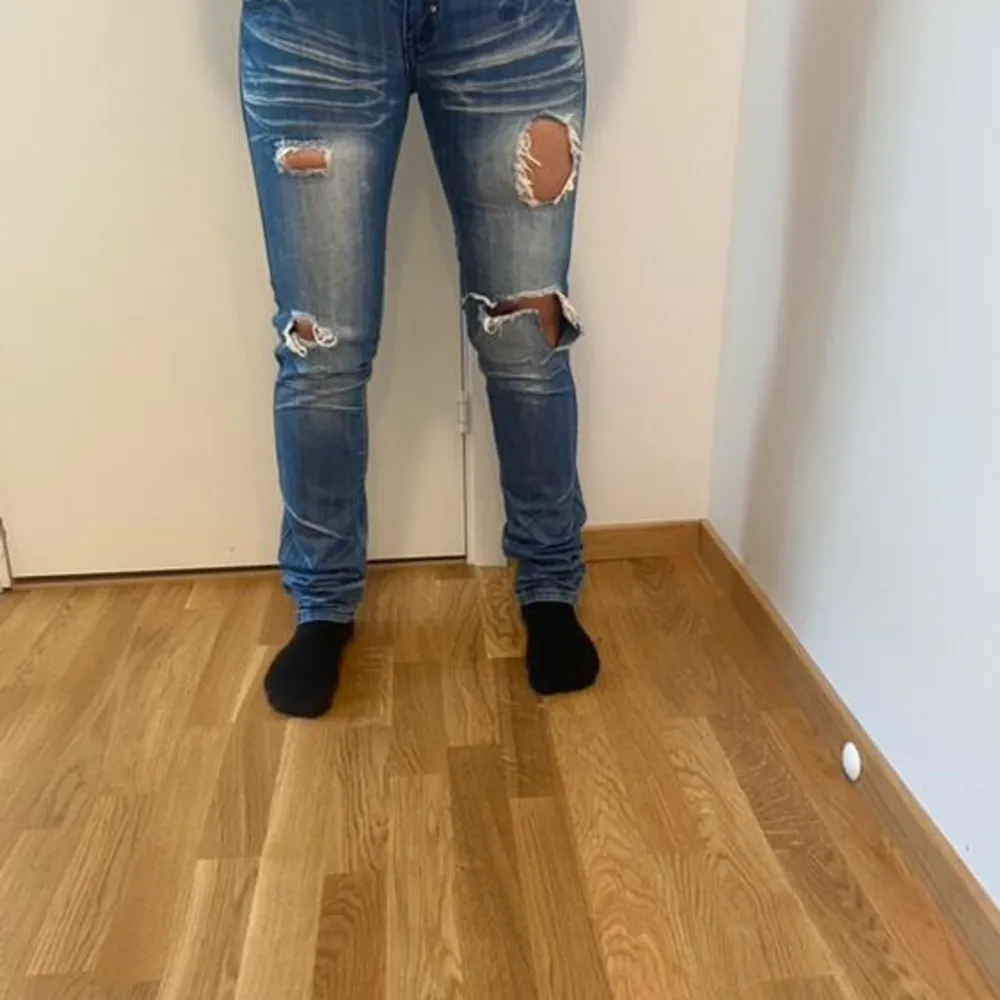 Säljer ett par coola blå jeans från Diesel med slitningar och hål för en trendig look. De har en normal passform och är perfekta för en avslappnad stil. Jeansen har klassiska fem fickor och en knappgylf. Perfekta för både vardag och fest!. Jeans & Byxor.