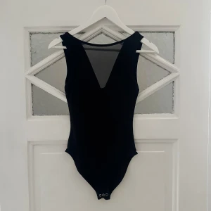 Svart body - Svart body med mesh v-ringning och lite djupare rygg. Storlek XS men passar även liten S