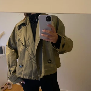 Kort trenchcoat - Säljer denna korta trenchcoat från Mango köpt på vinted då den tyvärr inte passade mig. I perfekt skick, som ny. Snörena går att ta ut om man vill det. Khaki färgad