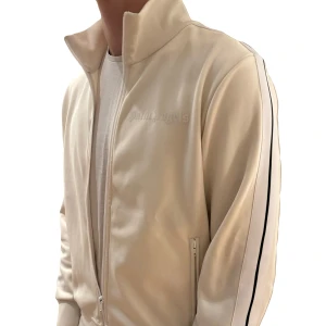 Palm Angels Zip Tröja - Tja säljer nu en riktig snygg Palm Angels Trackjacket i en krämvit färg. Storlek M men passar även S. Superfint skick och QR kod finns!