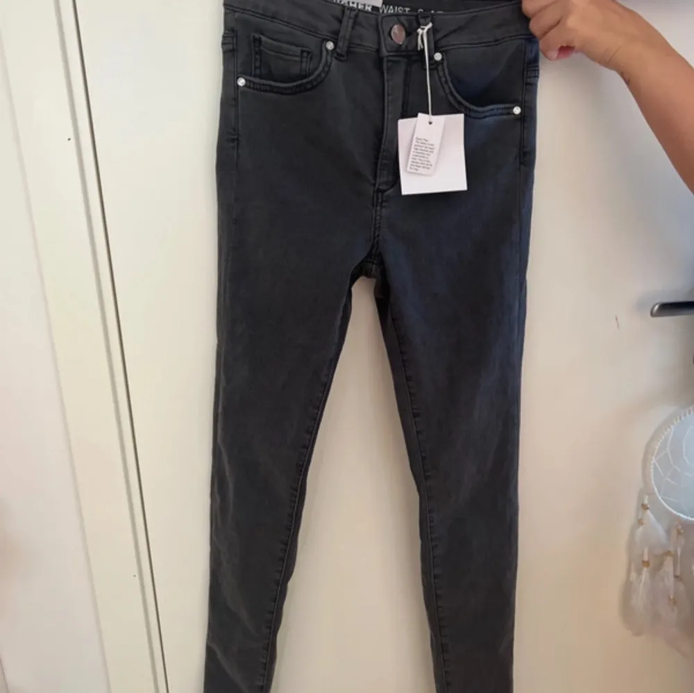 Säljer ett par helt oanvända high waist jeans i storlek S, i en snygg mörkgrå färg. Jeansen har aldrig använts och prislappen sitter fortfarande kvar! Perfekta för en trendig och stilren look. Passar utmärkt både till vardags och till fest. Först til. Jeans & Byxor.