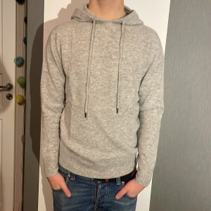 Merinoull Hoodie - En riktigt snygg hoodie i 100 procent merinoull! Storlek XS. Modellen är 178 cm lång. En riktigt snygg ljusgrå färg! Använd max 3 gånger, inga defekter! Hör av dig vid intresse eller minsta fundering!