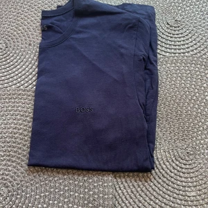 Mörkblå t-shirt från Boss - Snygg mörkblå t-shirt från Boss med diskret logga på bröstet. Perfekt för en stilren look. 