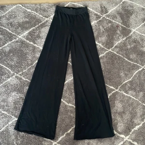 Svarta vida byxor från Bik Bok - Snygga svarta byxor från Bik Bok i en loose och wide stil. De är högmidjade och perfekta för en avslappnad look. Byxorna är tillverkade i ett mjukt material som ger en skön känsla hela dagen.