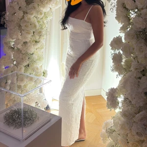 Vit långklänning med blommigt mönster - Elegant vit långklänning med smala axelband och blommigt mönster. Storlek M men passar en S lika bra, nypris 3000 mitt pris 1500