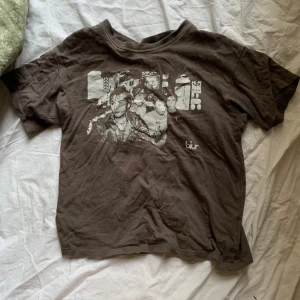 Brun t-shirt med Blur-tryck från H&M Divided - Cool brun t-shirt från H&M Divided med ett stort tryck av bandet Blur på framsidan. Perfekt för musikälskare som vill ha en unik stil. T-shirten har en klassisk passform och korta ärmar.